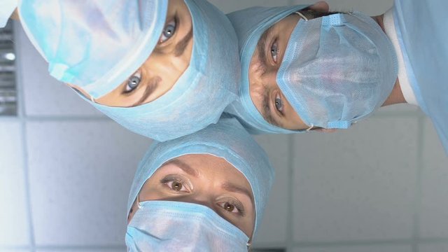 Clinic workers putting sterile mask before operation, plastic surgery teamwork