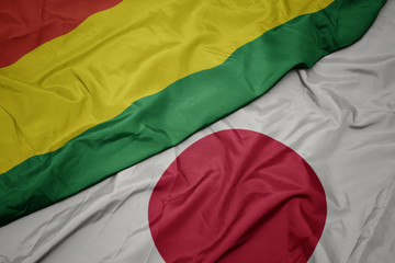 waving colorful flag of japan and national flag of bolivia.