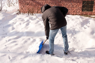 A teenager shoveling snow in his yard. The concept of a snowy winter.