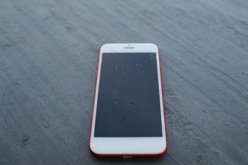 Modern broken mobile phone on a black marble background.