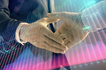 Multi exposure of forex graph on abstract background with two businessmen handshake. Concept of success on stock market