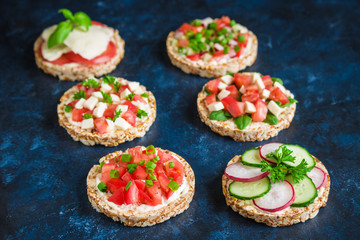 rice crisp cracker with chopped vegetables tomato cucumber radish parsley soft cheese .healthy snack