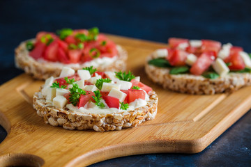 healthy sandwiches with rice cakes topped tomatoes soft cheese parsley salsa on cutting board