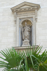 Fototapeta na wymiar Statue in a niche on the side of St. Stephens Basilica in Budapest, Hungary with palm in front