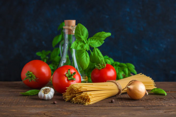 raw ingredients for cooking italian pasta. spaghetti tomatoes garlic basil olive oil onion