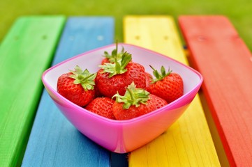 Strawberries in a bowl on a rainbow bench 