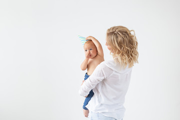 Single parent, motherhood and baby concept - Cheerful mother having fun with her little daughter in the studio, isolated on white background with copy space
