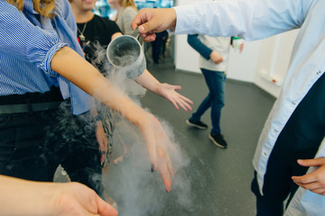 Chemical event at the birthday party: children's hands touch the smoke from liquid nitrogen.