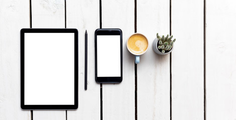 Office objects, devices with blank screens. White screen on smartphone and tablet on wooden table
