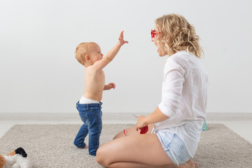Family and parenting concept - Cute baby playing with her mother on beige carpet