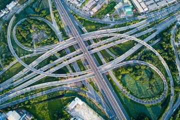 Foto op Aluminium Aerial view of road interchange or highway intersection with busy urban traffic speeding on the road. Junction network of transportation taken by drone. © zephyr_p