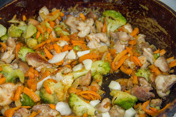 meat broccoli carrots onions garlic with sesame seeds all together in a pan. looks like a background