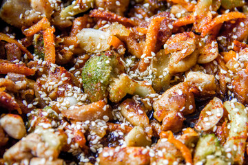 meat broccoli carrots onions garlic with sesame seeds all together in a pan. looks like a background