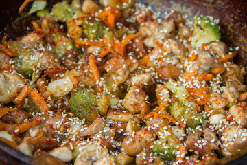 meat broccoli carrots onions garlic with sesame seeds all together in a pan. looks like a background