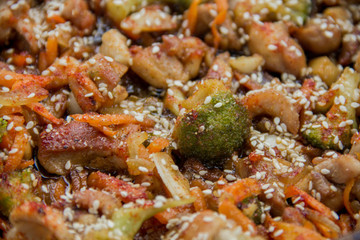 meat broccoli carrots onions garlic with sesame seeds all together in a pan. looks like a background