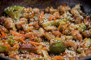 meat broccoli carrots onions garlic with sesame seeds all together in a pan. looks like a background