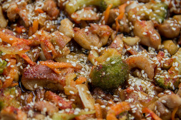 meat broccoli carrots onions garlic with sesame seeds all together in a pan. looks like a background