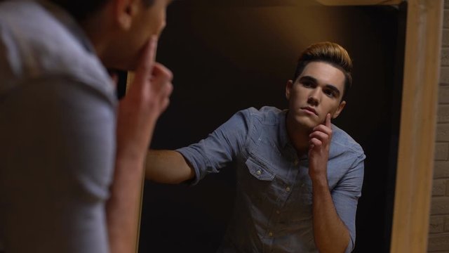 Transgender man looking in mirror, feels ugly or weird being male, insecurities