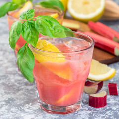 Refreshing lemonade with rhubarb, lemon, sparkling water and basil in a glass, square
