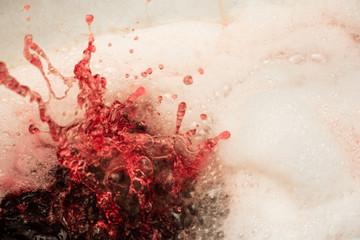 Fototapeta premium Soapy foam painted red with splashes is close