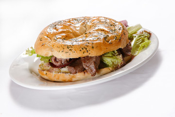Bagel and croissant of ham, meat and lettuce with cherry tomatoes.