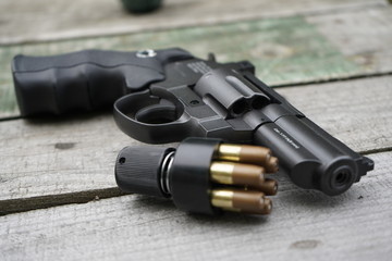 Obraz premium Air gun with cartridges on a wooden background.