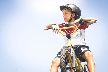 Young cyclist with bmx waiting to start. Trendy young boy wearing helmet riding a bicycle looking...