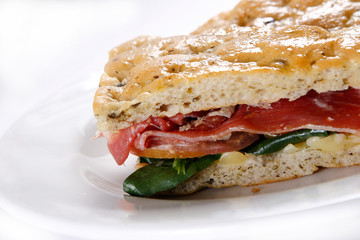 Traditional bread sandwich with serrano ham, cheese and spinach leaves.