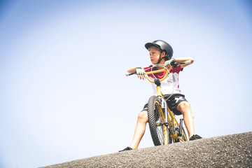 Young cyclist with bmx waiting to start. Trendy young boy wearing helmet riding a bicycle looking...