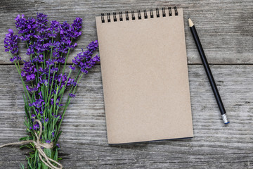 Lavender flowers with blank paper notebook and pencil on rustic wooden background. flat lay. mock up