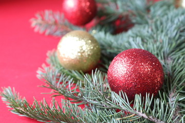 Green fir branch with red and gold balls on a red background for a Christmas card.