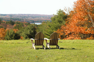 wooden adirondack chairs overlooking to a beautiful fall view of a lake and mountains