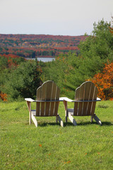 wooden adirondack chairs in vertical with lush green grass and fall colors showing in the overlook 