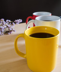 Three cup of coffee lined in a oblique line and focus at the yellow cup 