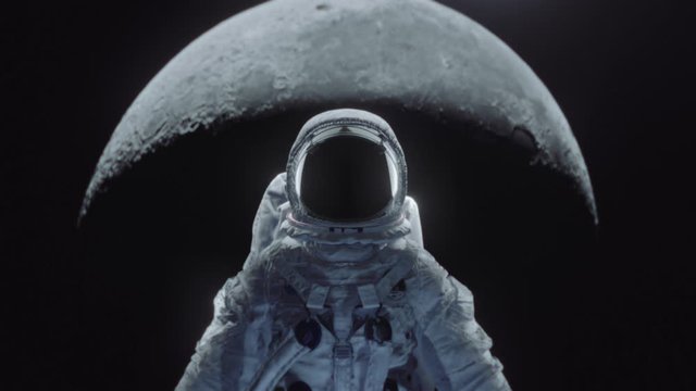 Dolly shot of an astronaut in spacesuit with moon in the background.