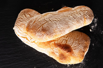 Food concept homemade artisan classic Italian style yeast dough Ciabatta bread on black slate board with copy space