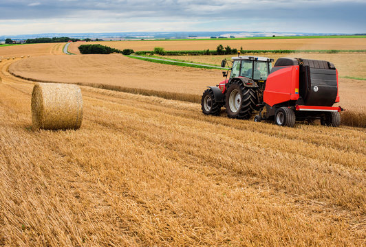 farmer in fields making straw bales