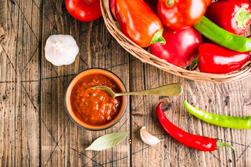 Adjika, spicy tomato sauce, vegetable snack on a wooden background