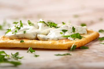 Salted craker with cheese cream and chopped parsley