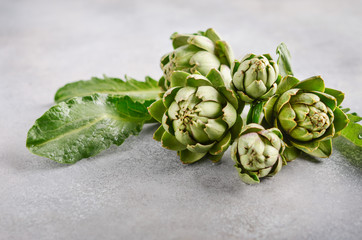 Fresh organic artichokes on a gray concrete background.
