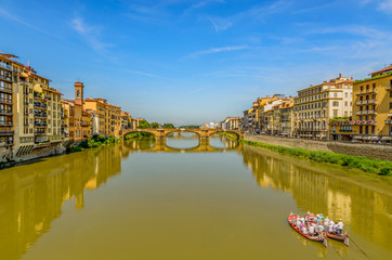 St Trinity Bridge stone bridge and boats on Arno River water and embankment promenade with buildings in historical centre of Florence  Tuscany, Italy