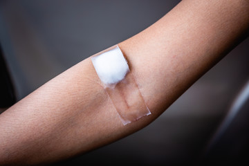Closeup of cotton closed the wound after blood collection or blood samples for examination, donation. Select focus.