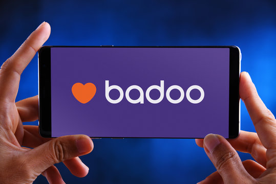 Hands holding smartphone displaying logo of Badoo