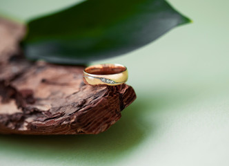 beautiful macro shot of golden wedding ring with some stuff on colored background