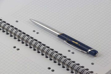 Ballpoint pen with notebook on white table