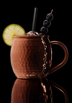 Icy cold cocktail with lime and blueberries in copper mug