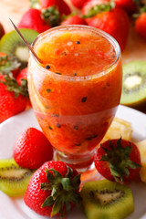 Strawberry juice with lemon served in glass with strawberries and kiwi.