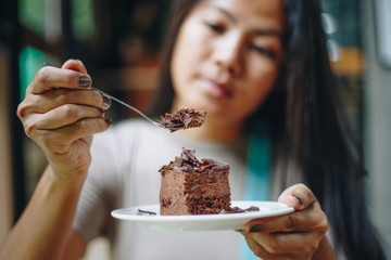 Asian woman eating chocolate cake at cafe