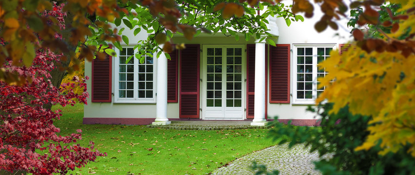 old classic style white home with windows, french door and a beautiful garden in autumn