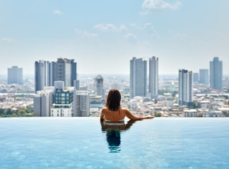 Young woman relax on the edge of the roof top swimming pool
